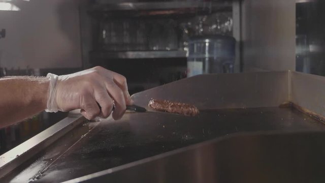 Chef cooking tossing and flips juicy meat for the burger, street food