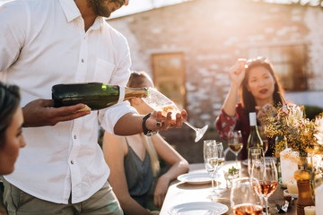 Man serving champagne to friends during party © Jacob Lund