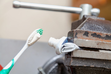 Toothpaste squeezed from tube onto brush squeezed vise