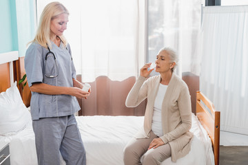 nurse giving medicine to senior patient