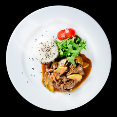 Delicious beef with oyster Mushrooms and rice served with tomatoes and sauce in a white plate isolated on black background. Autumn menu in an Italian restaurant. Top view, flat, overhead