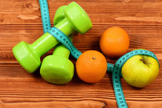 healthy eating concept, dumbbells weight with measuring tape, fruit