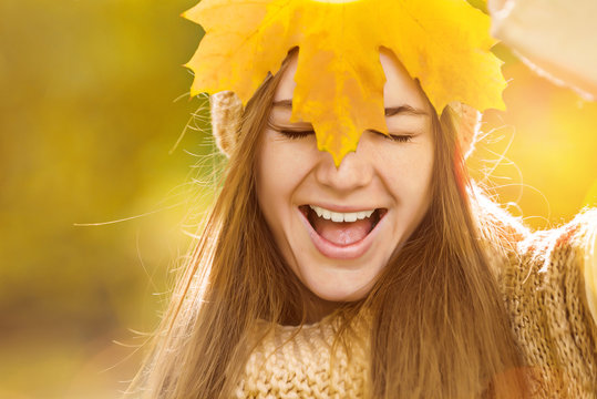 Positive woman face smiling and hide behind maple leaf