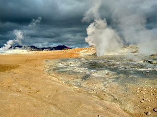 valley of geysers in Iceland, in the air a lot of steam, in the sky storm clouds