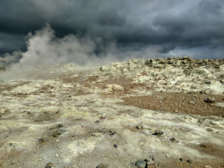 valley of geysers in Iceland, in the air a lot of steam, in the sky storm clouds