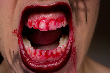 Closeup of Red lips of a young girl, with blood flowing by. Spooky woman smiling, mouth of woman in...