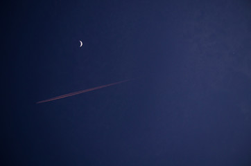 High clouds punctuated by the contrail of a jet airplane passing the conjunction of the Moon,...