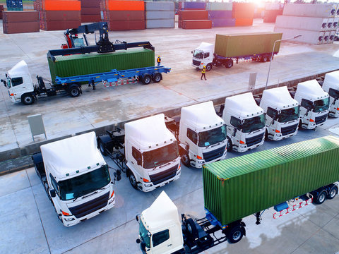 aerial view of loading forklift stacker handling cargo container loading to container trailer in import export logistic zone of port in background