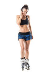 Happy relaxed woman with roller skates holding headphones and smiling looking down. Full body length portrait isolated on white studio background.