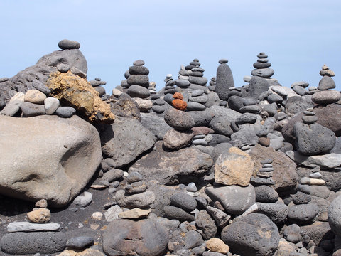 stacks and towers of pebbles and rocks against a blue summer sky