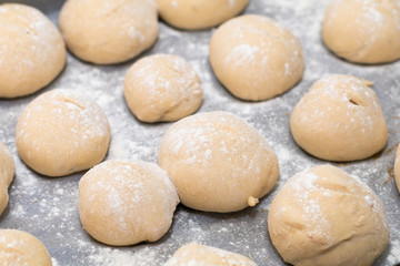 Authentic home kitchen, freshly made white bread rolls proving sprinkled with with flour ready for baking on tray