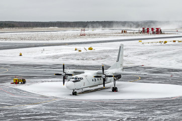 Passenger small airplane at the airport in winter in bad snow and blizzard weather.