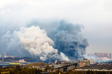 Fototapeta premium Fire in warehouses with dark and white huge smoke clouds.