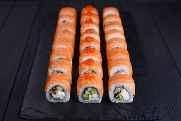Delicious california sushi rolls set on black slate, restaurant serving. Japanese food art
