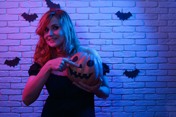 Young beautiful woman pointing at pumpkin in hand. Free space for text design. Halloween,...