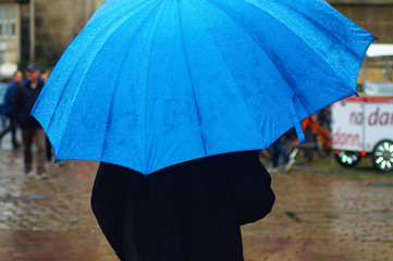 Mann mit blauem Regenschirm auf dem Prinzipalmarkt in Münster