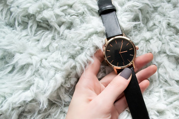 Elegant black watch in a female hand. Fashionable concept