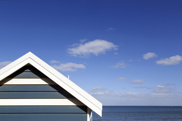 Close up of an iconic beach hut on Melbourne's Brighton Beach with a summer blue sky and ocean background