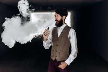 Young man with beard vaping an electronic cigarette outdoor. hipster smoke vaporizer.