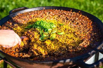 Cooking and making traditional Spanish Paella in iron cast pan.