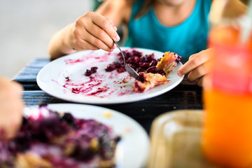 Children eating blueberry strudel with sugar on top.