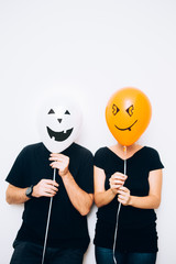 Couple hiding behind halloween balloons 