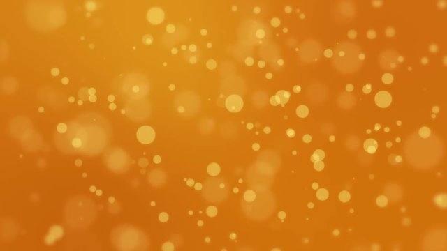Beautiful festive orange bokeh background with glowing yellow light particles.