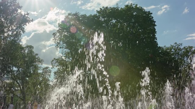 Water gushes and splashes in City Fountain. Trees are visible on the background of sunny sky. Outdoor. Sunny. Stabilised. Medium