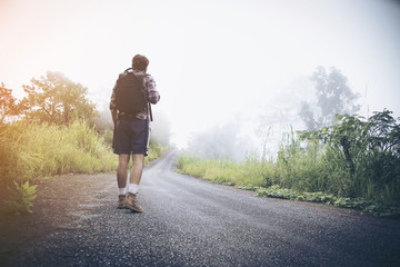 Traveler walking along the road to the mountains.