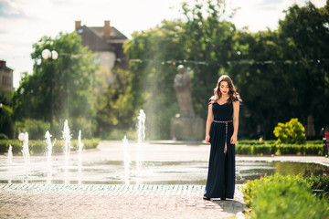 Fototapeta premium A girl is walking around the city, near a large fountain. Sunny day. Summer