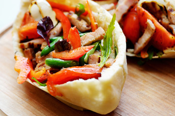 Stuffed with meat, tomato, onion, pepper, green beans, greens, basil, dressed with sauce and served on a wooden board