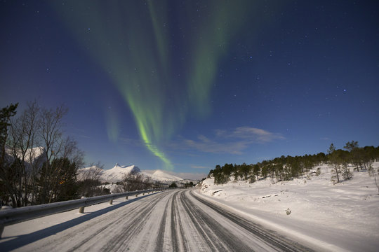 Aurora borealis over a moonlit landscape in northern Norway