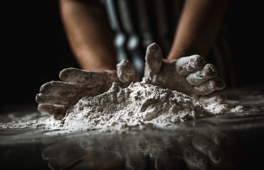 The man cook prepares flour products and meal-free flour on a glass table. Beautiful conceptual photo