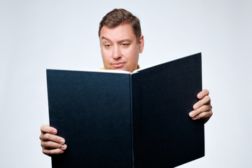 Caucasian man opening big book and with doubt looking in search of important information