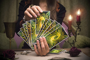 Tarot cards in fortune teller woman hands. Paranormal table.