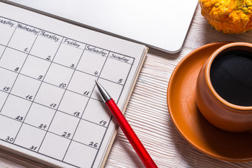 Computer and hand written calendar on wood desk