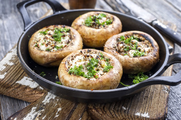 Traditional Italian mushroom caps stuffed with feta as close-up in a rustic frying pan