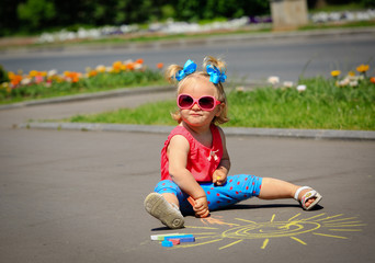 cute little girl drawing sun on a street