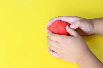 kid knead red play dough on yellow table