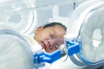Infant in incubator machine maintain healthy environment for newborn premature sick babies neonatal intensive care unit. - obrazy, fototapety, plakaty