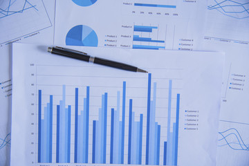 Pen on diagram chart and graphs business report with money, compass, calculator on desk of...