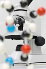 Fototapeta na wymiar Microscope with molecule model on table