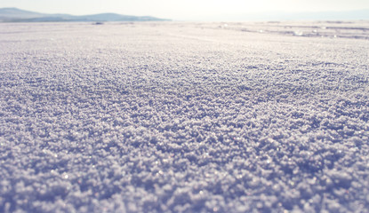 Fototapeta na wymiar Winter landscape. Snow field sparkling in the sun, surface snow texture. Christmas natural background. Lake Baikal