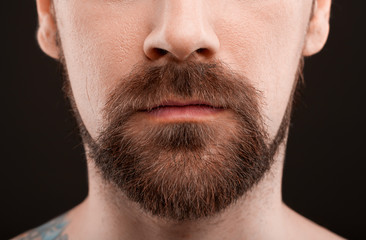 Closeup portrait of man with beard isolated at dark background.
