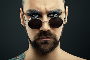 Obraz premium Portrait of Man with a beard in glasses and art makeup on dark background 