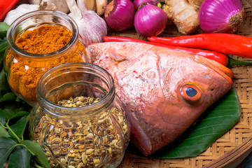 Raw red snapper heads ready for cooking with some spices on wooden cutting board