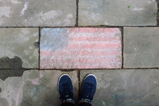 Low section of man standing on pavement near American flag 