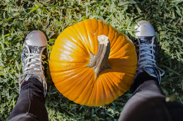 Big bright orange pumpkin at feet during autumn Halloween season.