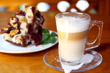 dessert at restaurant: cup of morning coffee - cappuccino and served piece of chocolate cake with walnut