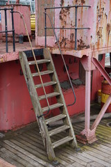 Fototapeta na wymiar Wooden ladder on deck of rusty scow